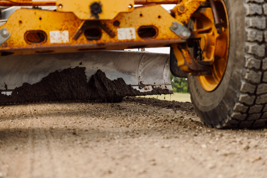 Close up of Grader leveling soil on road during mine haul road construction.