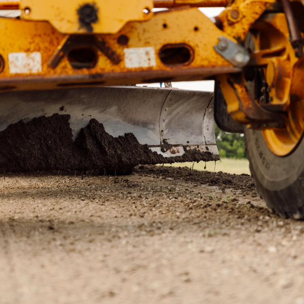 Close up of Grader leveling soil on road during road construction.